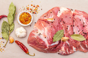Raw pork shoulder with spices. Bay leaf, garlic. On a stone background, close up, top view.