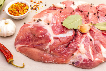 Raw pork shoulder with spices. Bay leaf, garlic. On a stone background, close up.