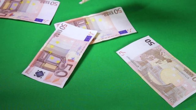 Soldi di carta da 50 Euro che cadono dall'alto su un tavolo con schermo verde. Video al rallentatore.