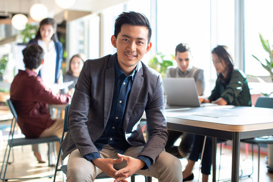 Young university teacher and his students in background