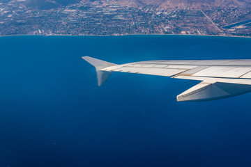 Fototapeta na wymiar Plane wing seen from window. Greek coastline on background