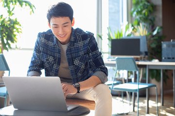 Young college student using laptop in classroom