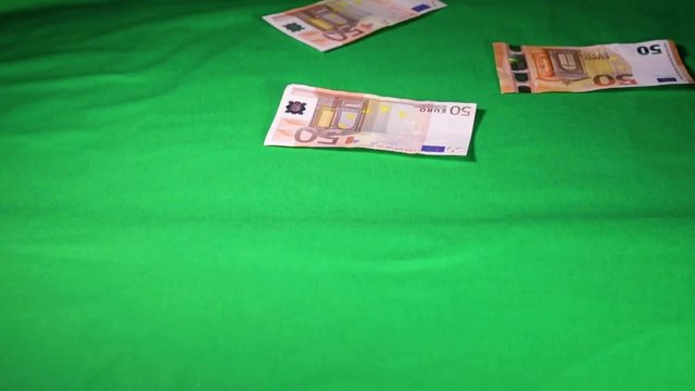 Soldi di carta da 50 Euro che cadono dall'alto su un tavolo con schermo verde. Video al rallentatore.