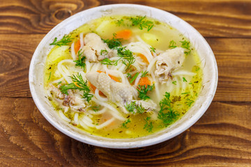 Chicken soup with noodles and vegetables on wooden table