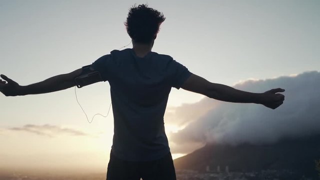 Male jogger with open arms looking at morning sunlight