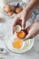 Making pancakes, cake, baking top view of baker hands crack an egg on flour. Concept of Cooking ingredients and method on marble background, Dessert recipes and homemade.