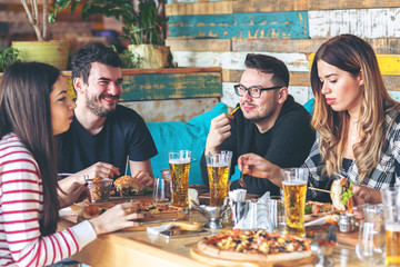 Young friends enjoy burgers and pizza at restaurant 
