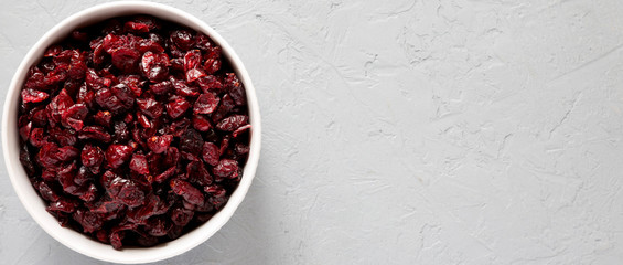 Dry organic cranberries in a bowl over gray surface, top view. Overhead, from above, flat lay. Copy space.