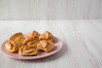 Home-baked cottage cheese biscuits on a pink plate over white wooden surface, side view. Copy space.