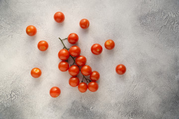 Bunch of cherry tomatoes on white textured stone concrete table, top view with copy space. Ingredients for cooking.