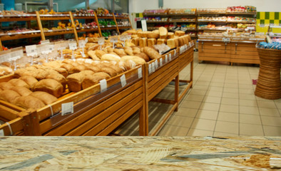 Department of baking in the supermarket. In the foreground is the top of a wooden table, counter.