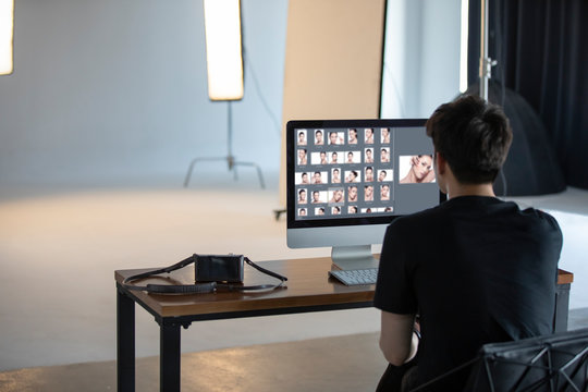 Young photographer retouching photos in studio