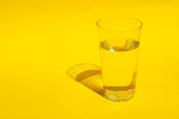 Glass Of Water Over Yellow Background. Abstract Colorful Background. Abstract Yellow Background.