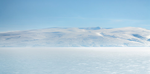 frozen lake with surrounding snow covered rocky mountains 