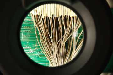 Close up of microelectronics engineering, electronic board circuit through a magnifying glass
