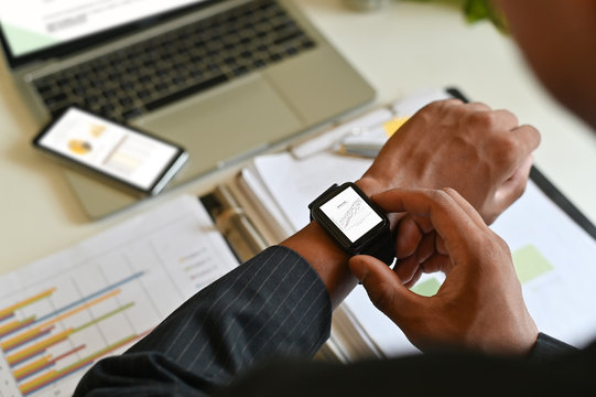 Businessman analysis data in smart watch on office desk.