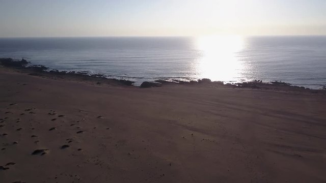 Las Tortolas beach aerial footage at Atacama Desert the sunset ray lights illuminate this amazing and idyllic beach in the middle of the desert, an arid awe landscape crashed by Pacific Ocean waters