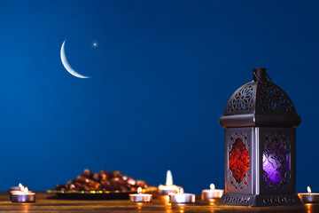 Moroccan, Arabic lantern and dates on on an old wooden table with the night sky and the Crescent...
