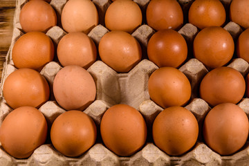 Pile of the hen eggs in paper tray on wooden table