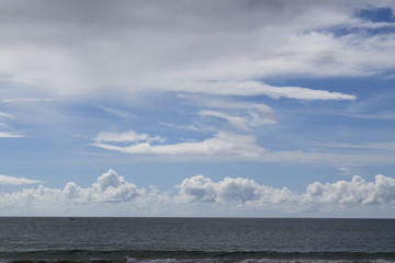 Praia, horizonte com faixa de mar  e céu azul com nuvem