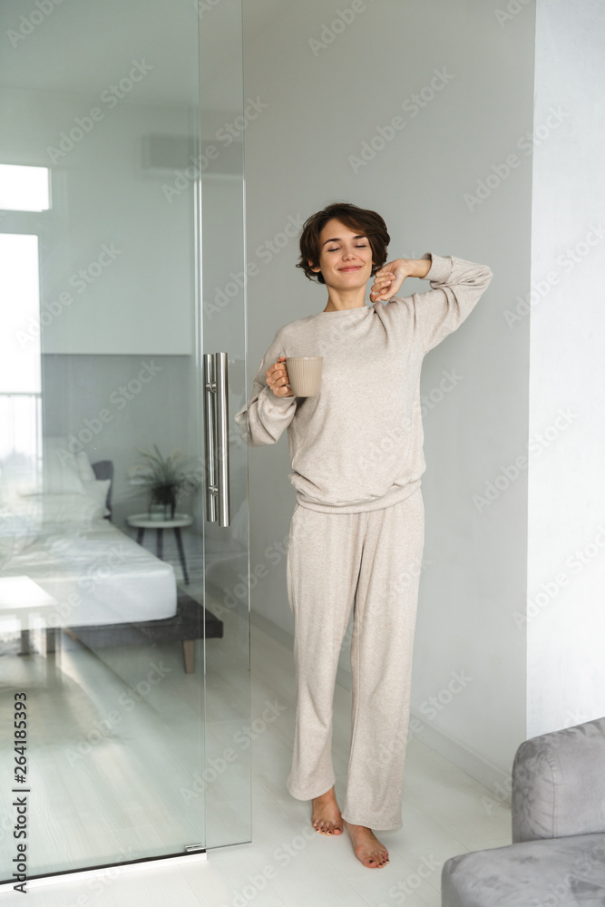 Wall mural Full length image of Cheerful brunette woman wake up