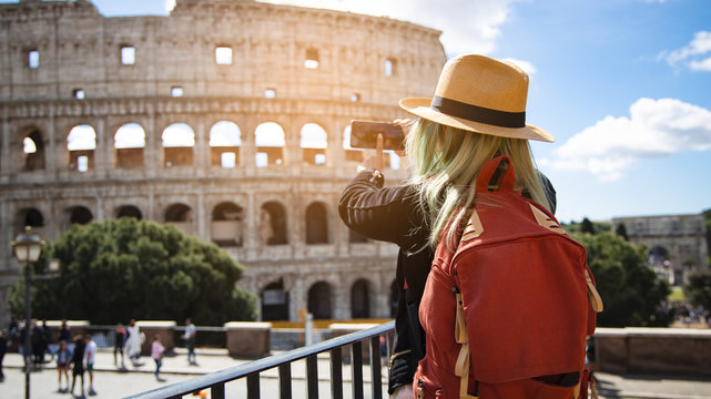 Back view of young woman with hat she's take a picture by smartphone at Colosseum in Rome, Italy. Rome architecture and landmark