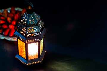 The Muslim feast of the holy month of Ramadan Kareem with dates on a tray on a dark background. Beautiful background with a shining lantern Fanus. Free space for your text. © Ievgenii Meyer