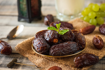 Ramadan food and drinks concept. Ramadan Lantern with Milk, dates fruit, grape and Mint leaves on wooden table background.