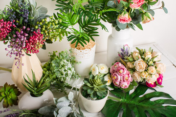 Various artificial flowers, bouquets in vases, succulents