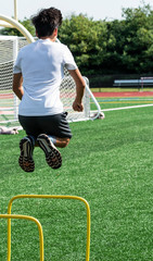 Obraz premium Young man jumping over two foot high yellow hurdles