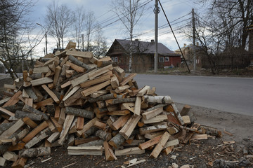 Hill of firewood against the background of the road and the house
