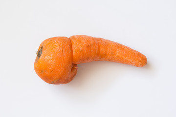 Deformed carrot on white background. Strange funny ugly vegetables. Misshapen produce problem, food waste concept. Top view, flat lay, copy space.