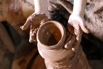 hands of a child who makes on a potter's wheel a jug made of clay
