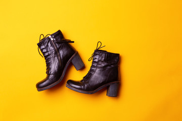 Elegant women black heeled boots. Top view of black boots on a yellow background.