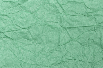 Close up top view of beautiful crumpled green pastel paper texture. Horizontal color photography.