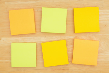 Six blank sticky notes on textured desk wood background