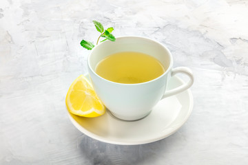 Obraz na płótnie Canvas A photo of a cup of tea with a slice of lemon and mint leaves, with a place for text