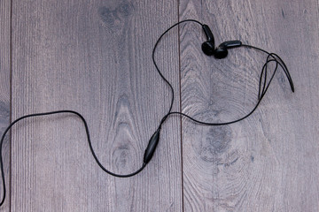 Earphones in shape or heart on wooden background. Flat lay, copy space.