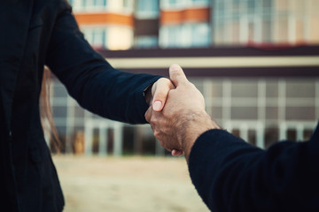 Fototapeta premium businessmen shaking hands on background of building