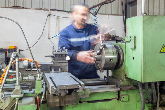 Heavy industrial worker operator working with lathe machine