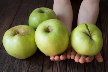 children's hands holding green apples on a wooden table, healthy food