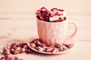 Turkish delight in a small coffee cup and dried rose buds. Nougat with flower petals