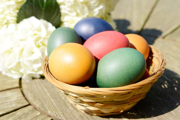 Fototapeta na wymiar Easter eggs eggs in the basket standing on table in the garden