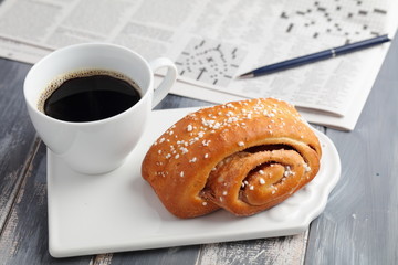 Weekend breakfast with coffee, cinnamon  bun  and crossword
