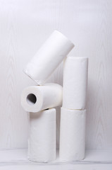 Vertical shot of rolled paper towels on the marble floor against white wall