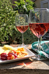 Close up of a pair of rose wine glasses with fruit and cheese