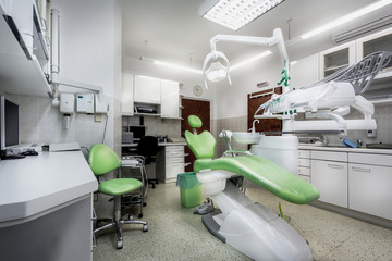 Ordinary dental surgery with a dental chair and related equipment in the wide-angle image. The...