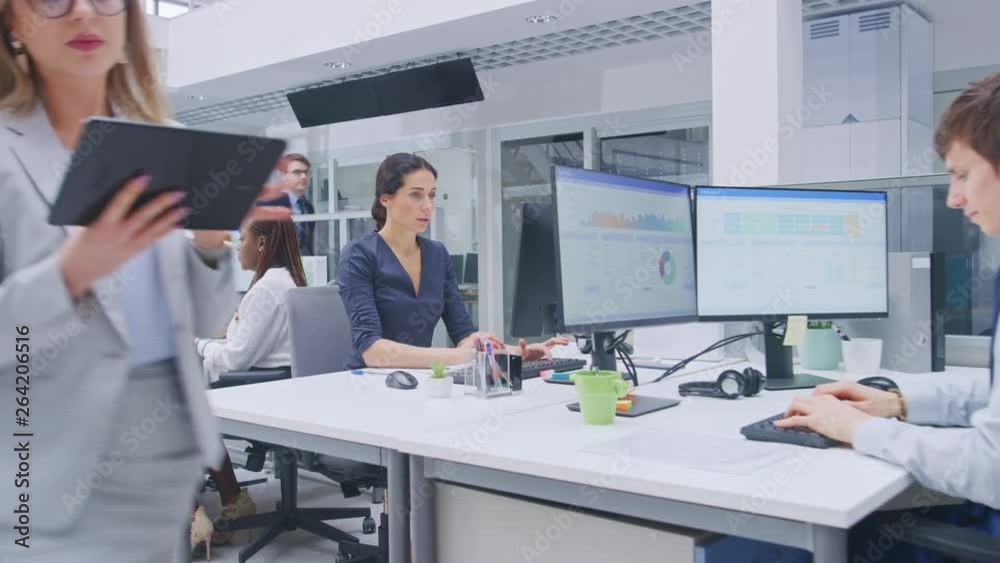 Poster in the big busy corporate office camera zoom in on female manager using desktop computer, around him