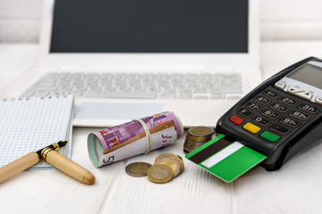 Laptop, terminal with credit card and euro in roll