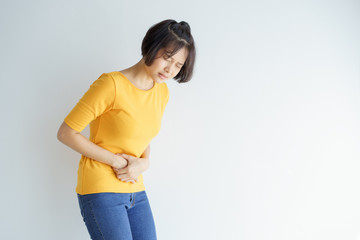 Young asian woman having painful stomachache on white background.Chronic gastritis. Abdomen bloating concept.